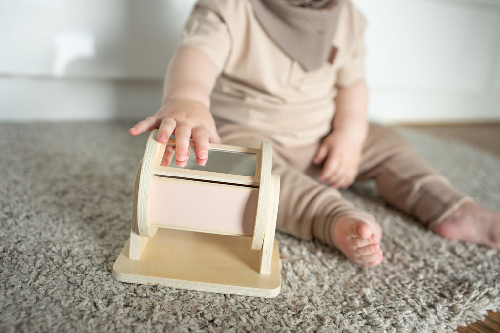 Child playing with a wooden toy on a carpeted floor